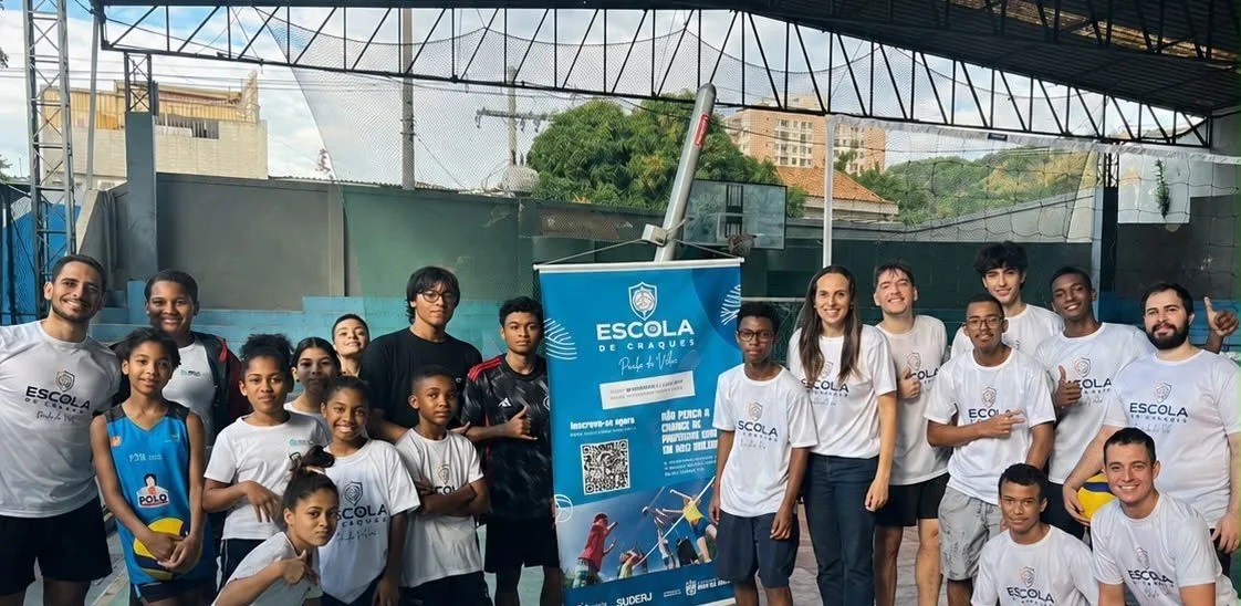 Paula do Vôlei ao lado de crianças, jovens e professores em uma quadra, durante atividade da Escola de Craques.